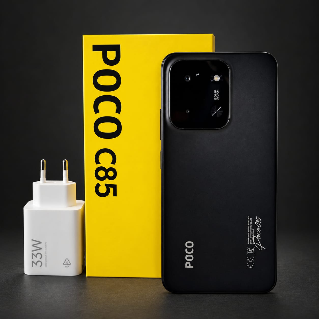 Celular POCO C85 preto com a caixa amarela e o carregador de 33 W
